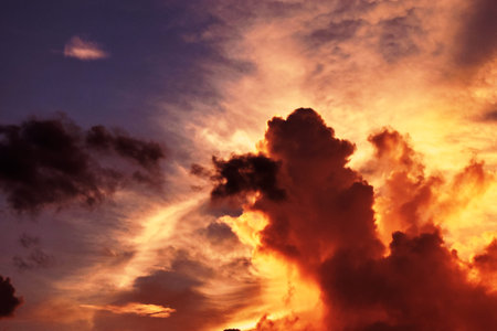 Horizon is orange with light beam shooting out from behind dark red clouds on blue sky, Beautiful...