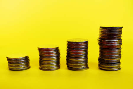 Four stacks coins row on yellow background, Placing  copper coin in the  higher graph bars throughout. Financial and commit business conceptの写真素材