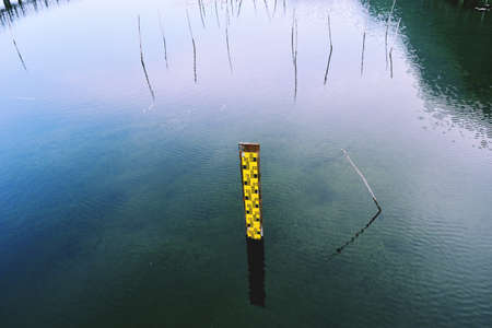 Water level gauge or Staff Gauge on blue water in the wetlandの写真素材