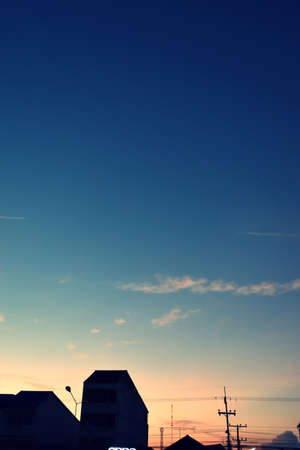 Silhouette of the building and electricity poles with beautiful blue sky at sunset, Photos back - light at the horizon began to turn orangeの写真素材