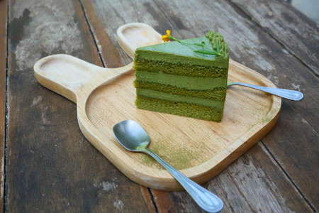 Japanese Matcha green tea with red bean cake, Sweet food with spoon and fork on a wooden plate with brown table in backgroundの写真素材