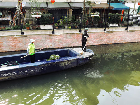 Bangkok Thailand - March 19 , 2021 : Staff was cleaning and using the net to scoop up the debris in the water onto the boat on Ong Ang canalのeditorial素材