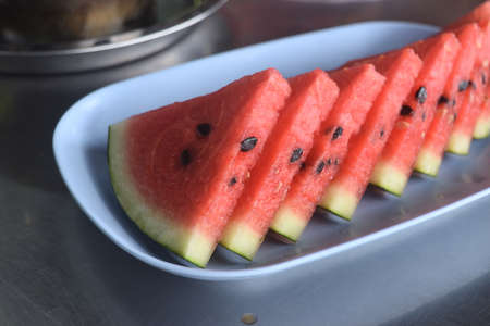 Sliced of watermelon in blue dish on table , Red juicy fruit flesh with green crustの写真素材