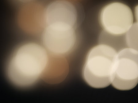 Night city light bokeh background for the celebration of the holiday season, Colorful light circles spread on brown with orange with yellow and white from indoor lightingの写真素材
