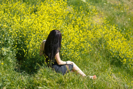 an attractive girl walks through colored meadows against the background of the sea and mountains.の写真素材