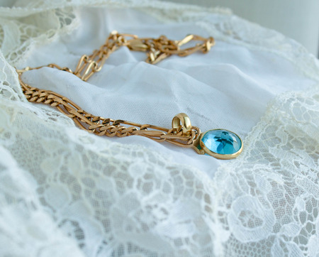 Gold Necklace with aquamarine stone on retro style white lace handkerchiefの写真素材