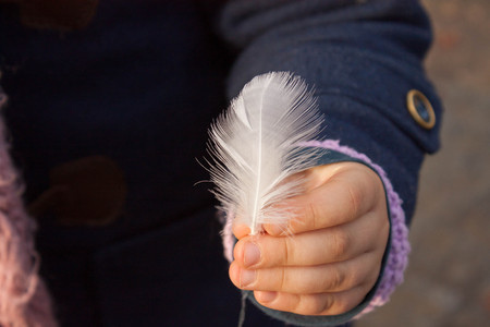 white girl with a bird feather in her hand showing it to cameraの写真素材