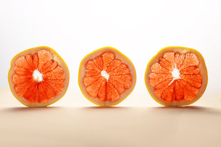 three round slices of ripe grapefruit vertically on a white backgroundの写真素材