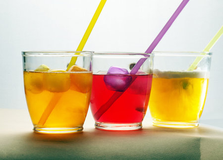 round slice slice of juicy grapefruit with two glass cups with yellow and red drinks with strawsの写真素材