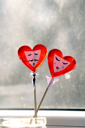 two heart-shaped lollipops with painted male and female facesの写真素材