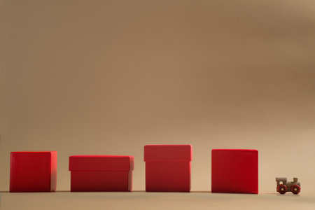 small wooden train with red gift boxes in a row on a beige backgroundの写真素材