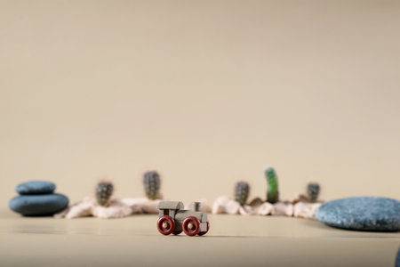 background image of wooden toy steam locomotive in desert with stones and cactuses on beige backdropの写真素材