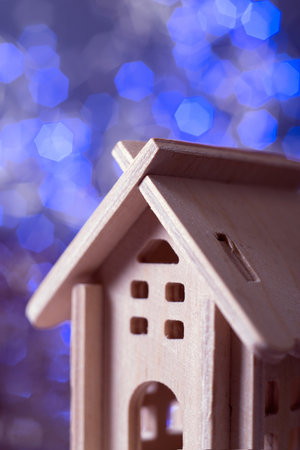 small decorative plywood house close-up against the background of blue bokeh lightsの写真素材