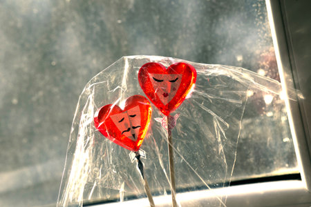 Two red heart-shaped lollipops in a plastic bag on the windowsillの写真素材