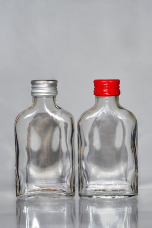 Two empty plastic bottles with red caps on a gray background with reflectionの写真素材