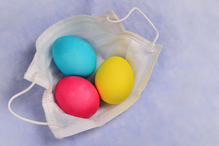 Colorful easter eggs with a medical mask on a blue backgroundの写真素材