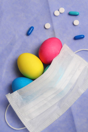 Colorful easter eggs with medical mask on a blue background.の写真素材