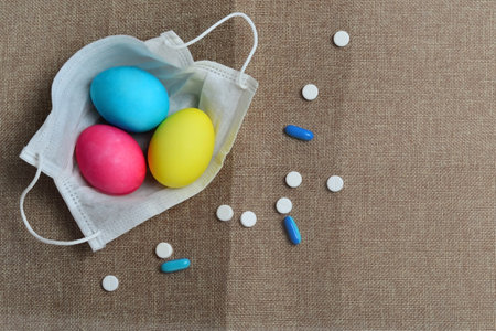Colorful easter eggs in a medical mask on a brown backgroundの写真素材