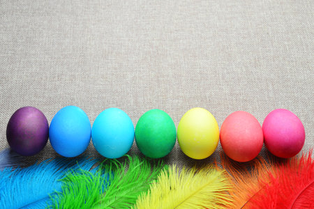 Colorful easter eggs and feathers on burlap background with copy spaceの写真素材