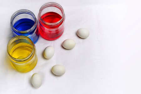 Colored paints in glass jars and eggs on a white background.の写真素材