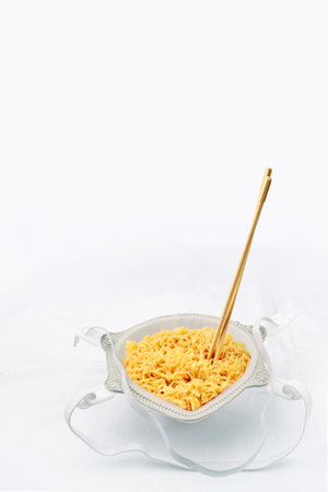 Instant noodles in a bowl with wooden chopsticks on a white backgroundの写真素材
