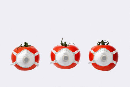 Tomatoes wearing medical mask on white background. Corona virus concept.