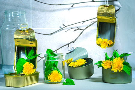 yellow dandelion flowers in a glass jar with a bottle of oilの写真素材