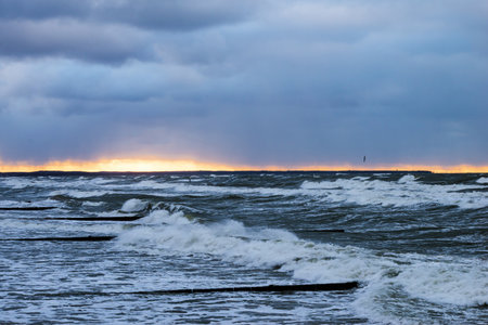 Stormy Baltic sea at sunset. Dramatic sky, glowing clouds, waves and water splashes. Latviaの写真素材