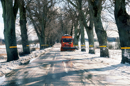 A red kamaz snow plow is moving on a snowy roadの写真素材