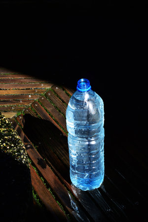 Plastic bottle of water on wooden table. Black background. copyspace.の写真素材