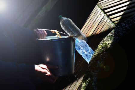 Man throwing plastic waste into a trash can at the edge of a wooden pierの写真素材