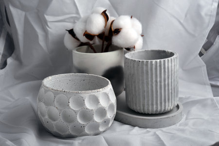 Ceramic flower pots and cotton flowers on white fabric background.の写真素材