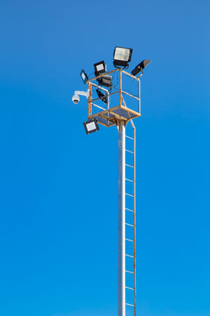 Pole with spotlights and CCTV camera at a ski resort. Against the background of the blue sky....