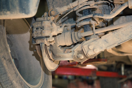 The suspension hub and rear caliper are old and rusty. In the garage, a man changes parts on a...