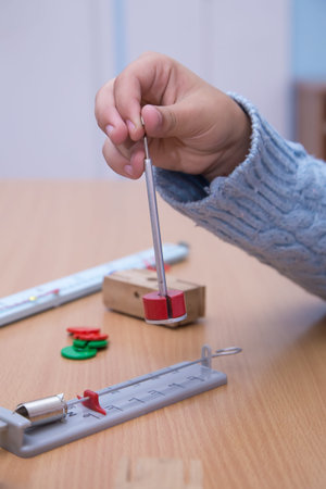 Close-up of a physical pendulum in a students hand. A schoolboy performs a task at the workplace....