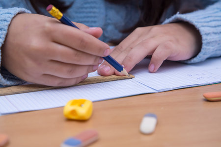 A student in a notebook works with a pencil with a ruler. A schoolboy performs a task at the...