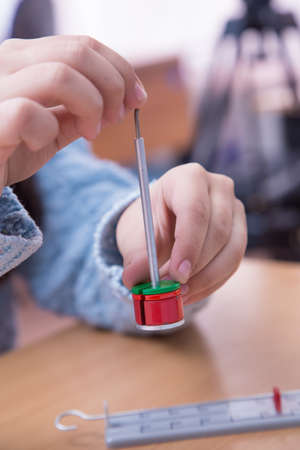 Pupils hand put weight on the physical barbell close-up. A schoolboy performs a task at the workplace. The concept of childrens education, teaching knowledge, skills and abilities.の写真素材
