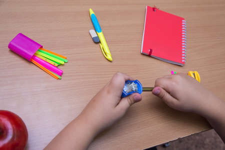Close-up hands of a student sharpen a pencil. A schoolboy performs a task at the workplace. The concept of childrens education, teaching knowledge, skills and abilities.の写真素材