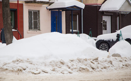 A loose snowdrift by the road against the backdrop of a city street with cars. On the road lies...