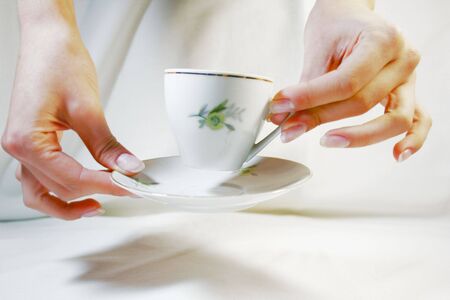 Two hands holding a cup and a saucerの写真素材