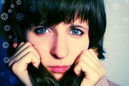Cross-processed photo of a woman who looks straight into camera with sad eyes and snowflakes surrounding herの写真素材
