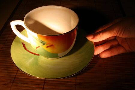 human hand is touches saucer with tea cup on itの写真素材