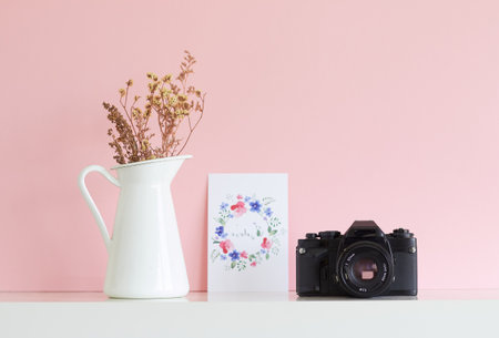 analogue camera floral postcard and white vase with dry flowers on a pink backgroundの写真素材