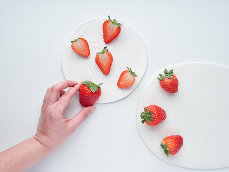 strawberries female hand picking a strawberrie on a flat lay compositionの写真素材