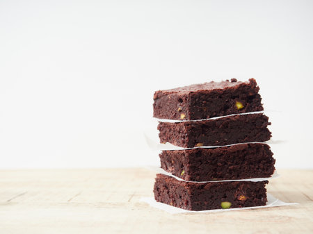 square brownie portions stacked with paper between them on a wooden table with a white backgroundの写真素材