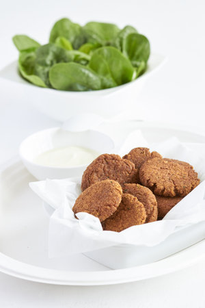 falafel on a white plate with green spinach and sauceの写真素材