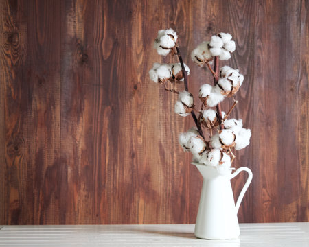 cotton flower in a white jar on a white table, wooden backgroundの写真素材