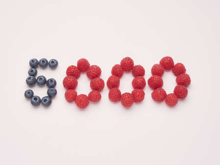 5000 five thousand number made with raspberries and blueberries on a pink backgroundの写真素材