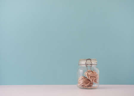 glass jar with whole wheat tagliatelle nest pasta. Front view with, copy space, blue backgroundの写真素材