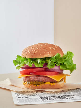 cheeseburger focus on foreground, a lot of green fresh lettuce, red onion, tomato slices and picklesの写真素材